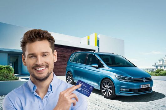 Mann steht vor blauem parkenden VW